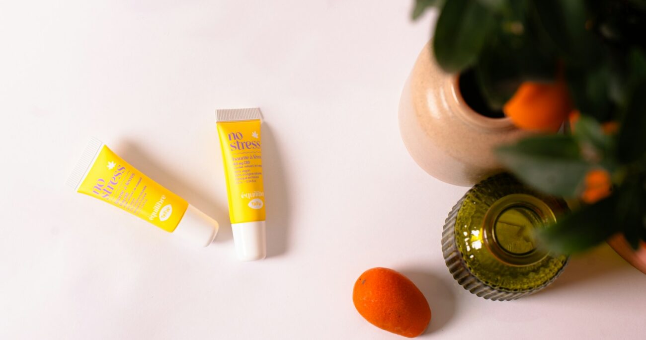 a bottle of lip butter next to some oranges